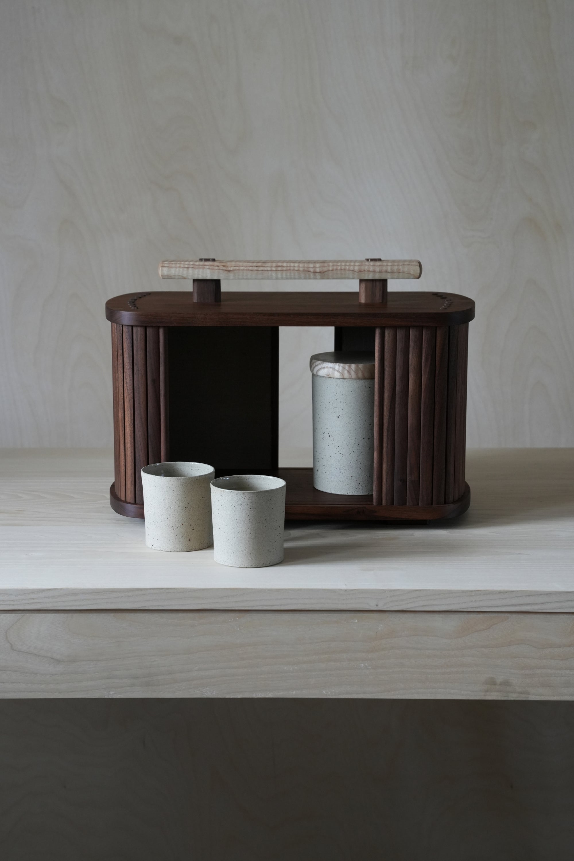 Wooden box with ceramic cups and tambour doors on a wooden surface
