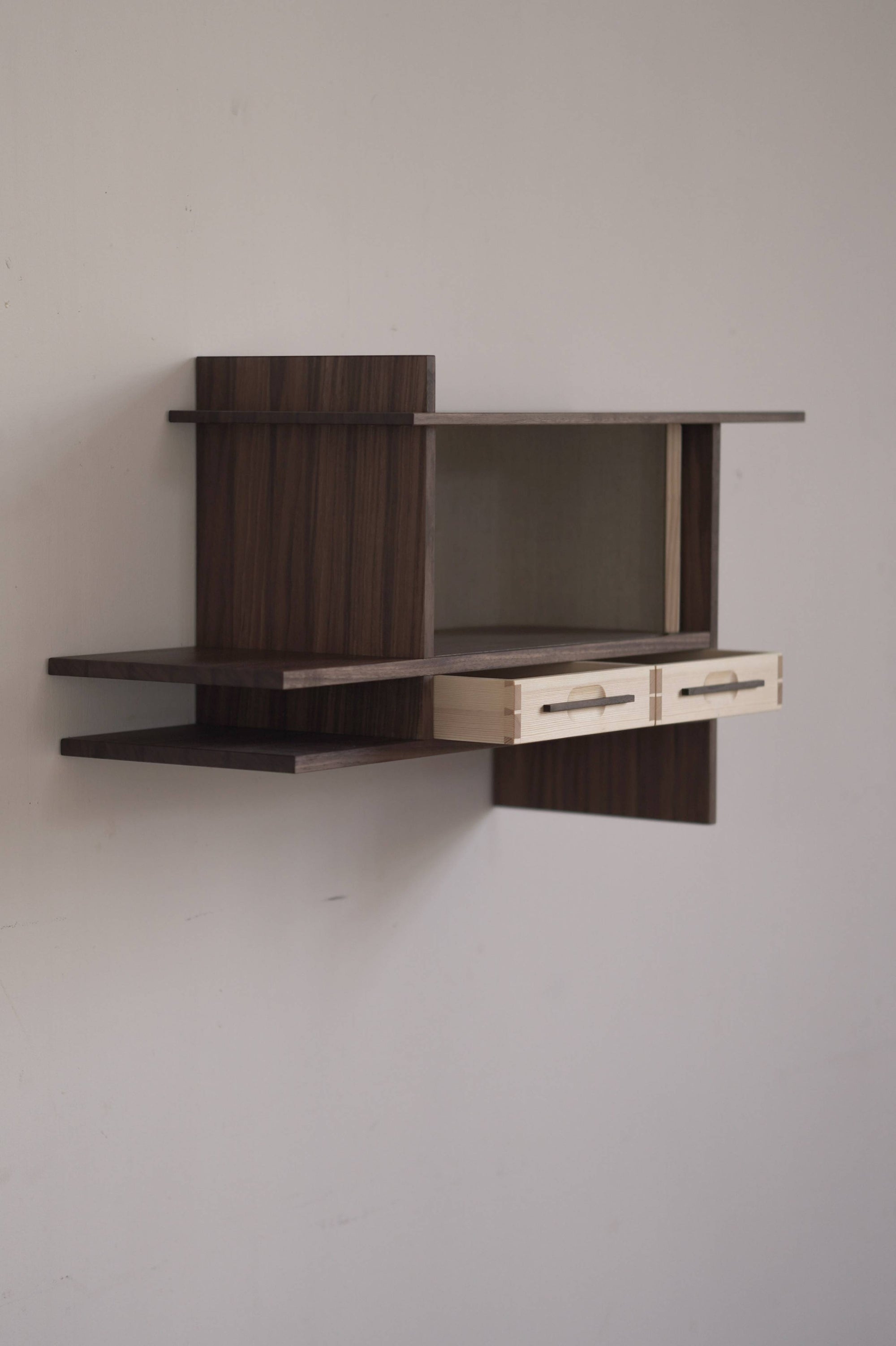 Wall-mounted wooden cabinet with two small drawers on a plain wall.