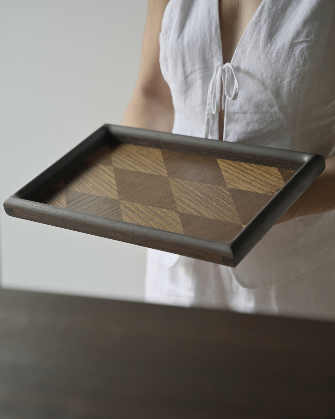 Person in a white linen top holding the fumed oak parquet tray, showing its size