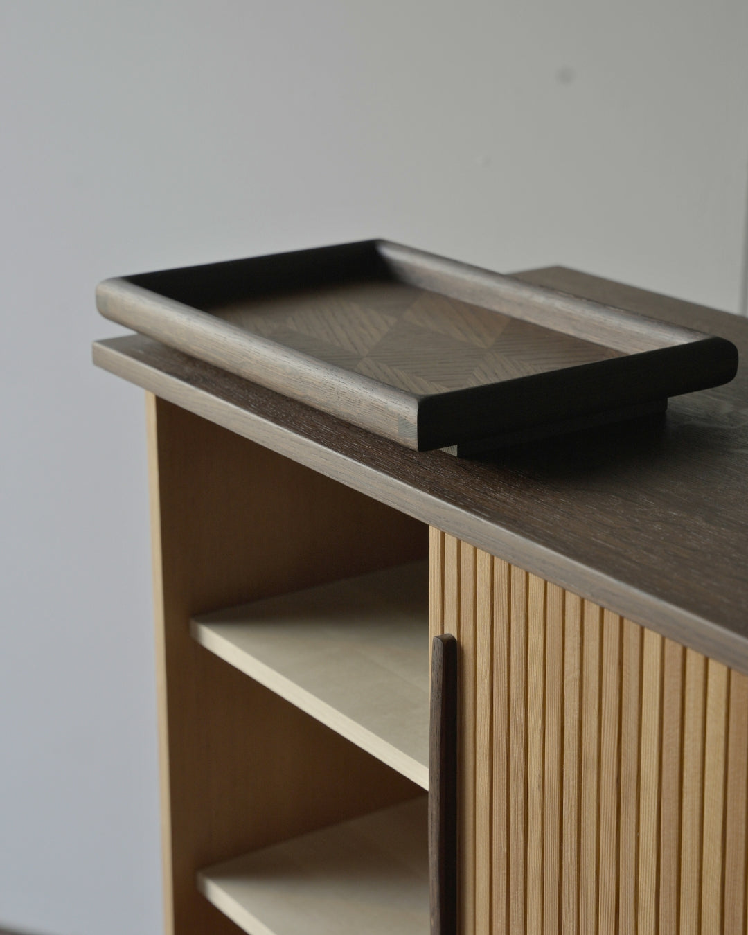 Fumed oak tray with a parquet surface placed on a sideboard with fluted doors