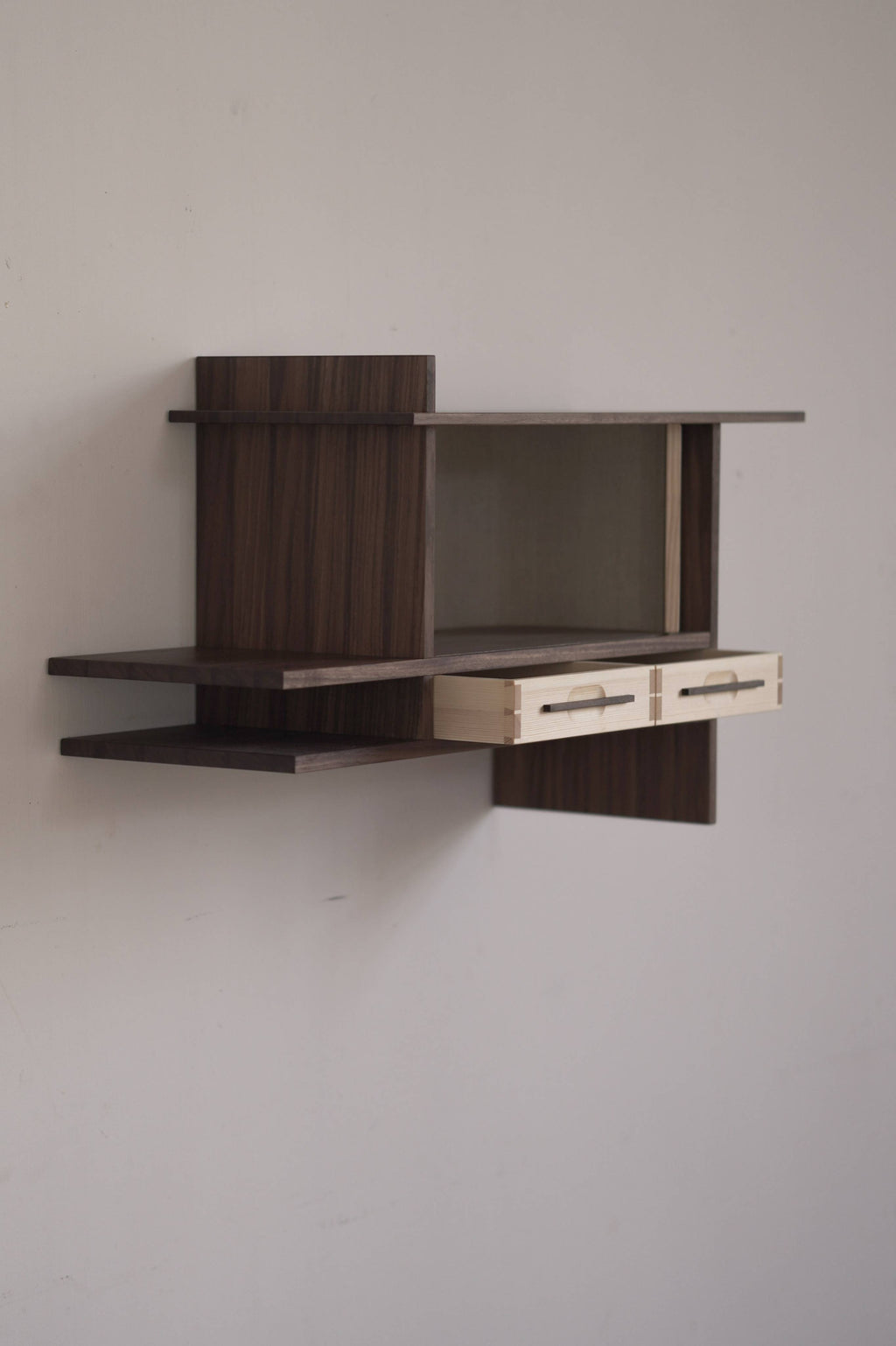 Wall-mounted wooden cabinet with two small drawers on a plain wall.