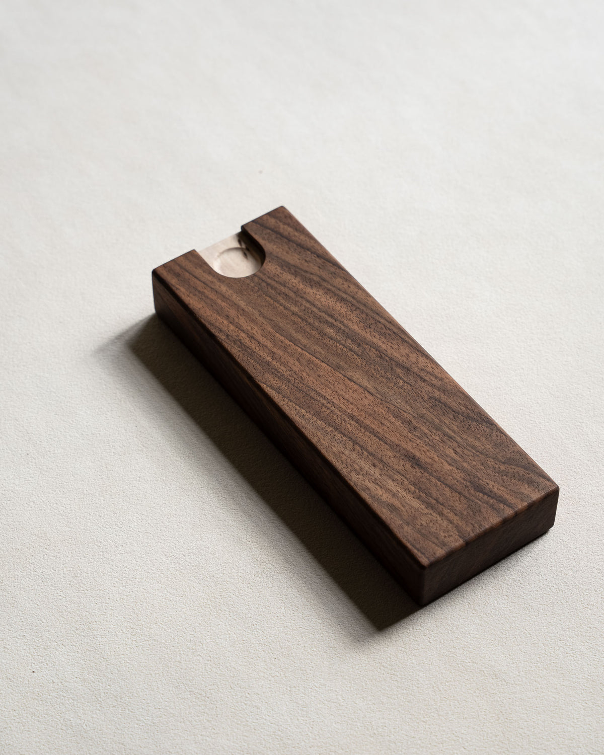 Underside of the walnut pill box, showing the small finger recess used to slide the tray open