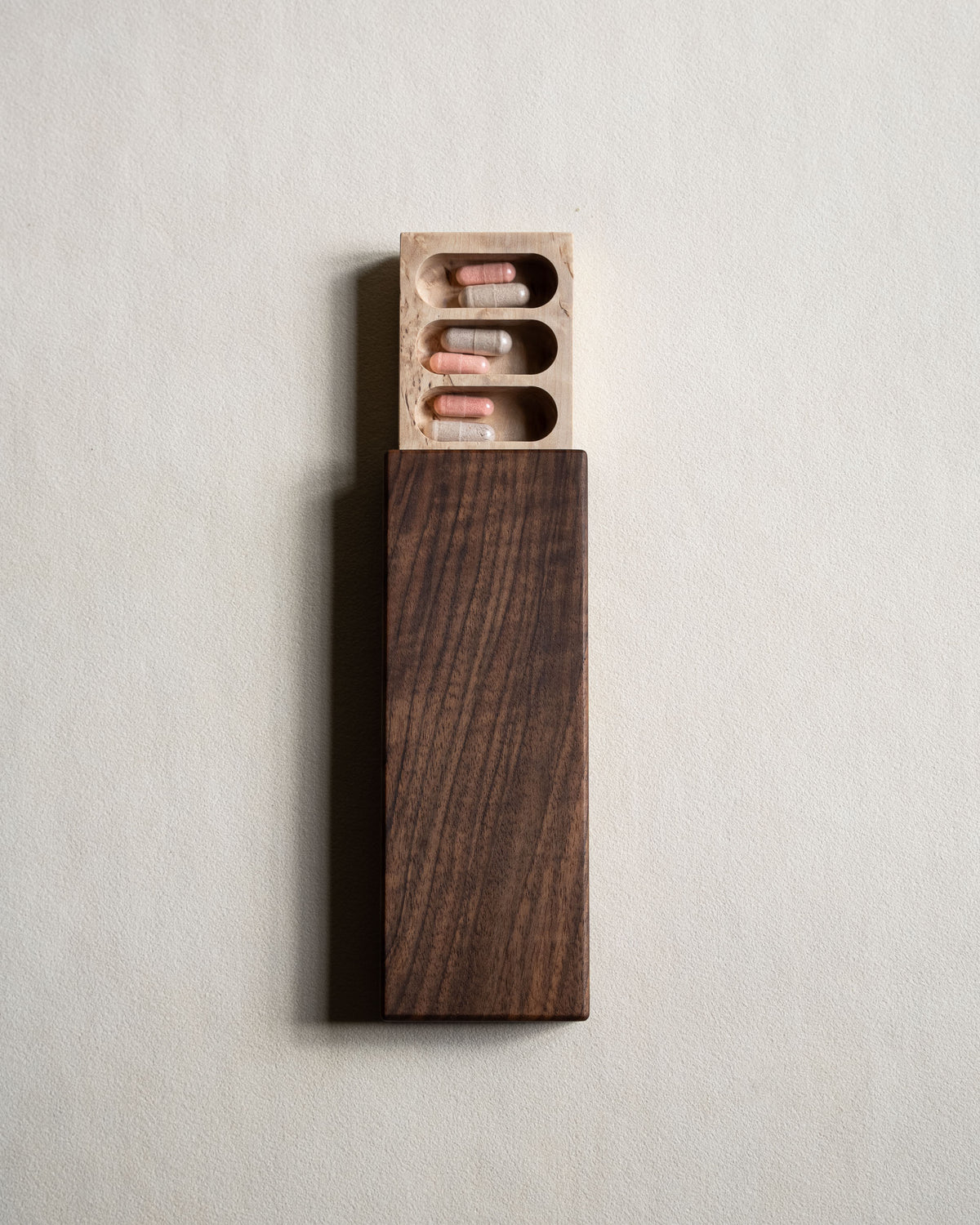 Walnut pill box seen from above, with the masur birch tray slid out to show three compartments