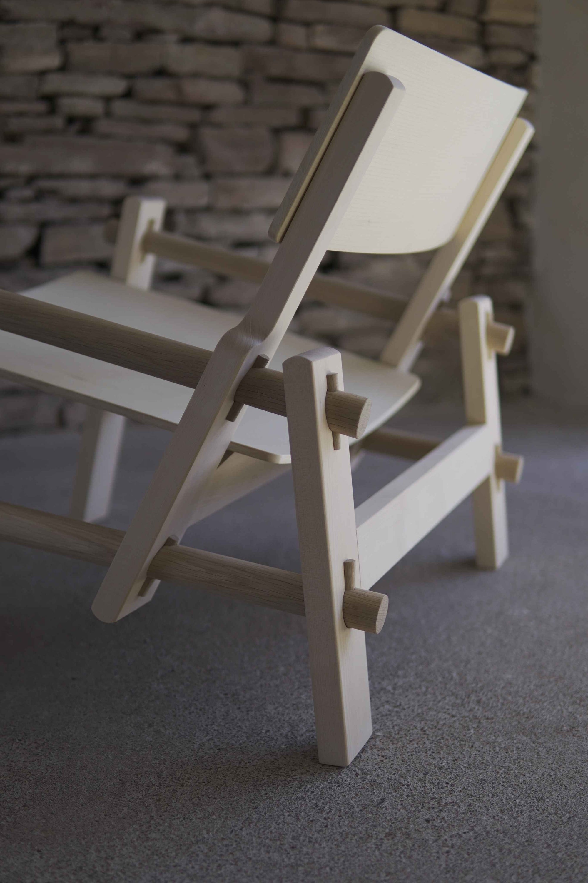 Wooden chair with a minimalist design against a stone wall background