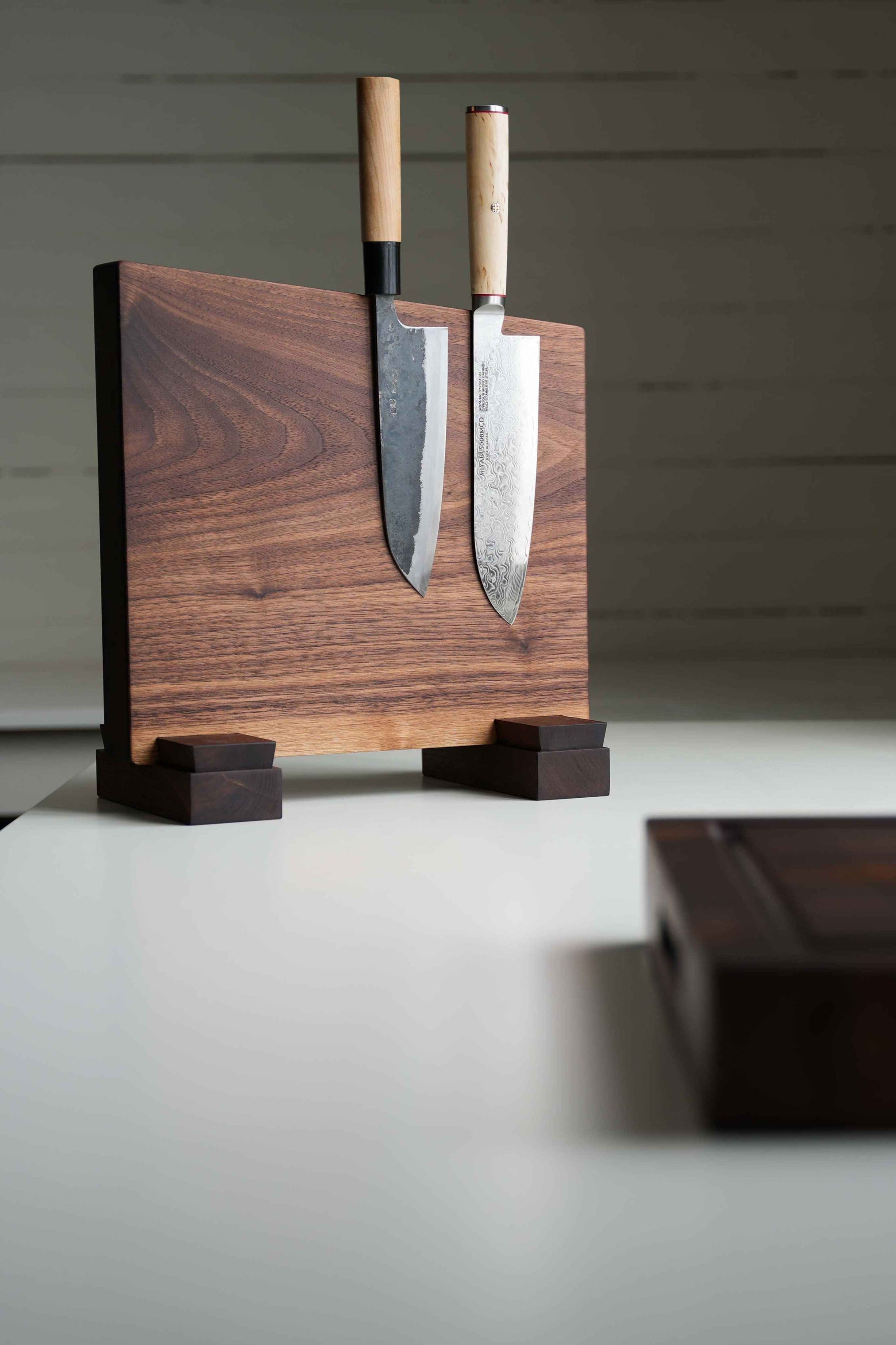 Walnut wood knife block with two knives on a neutral background