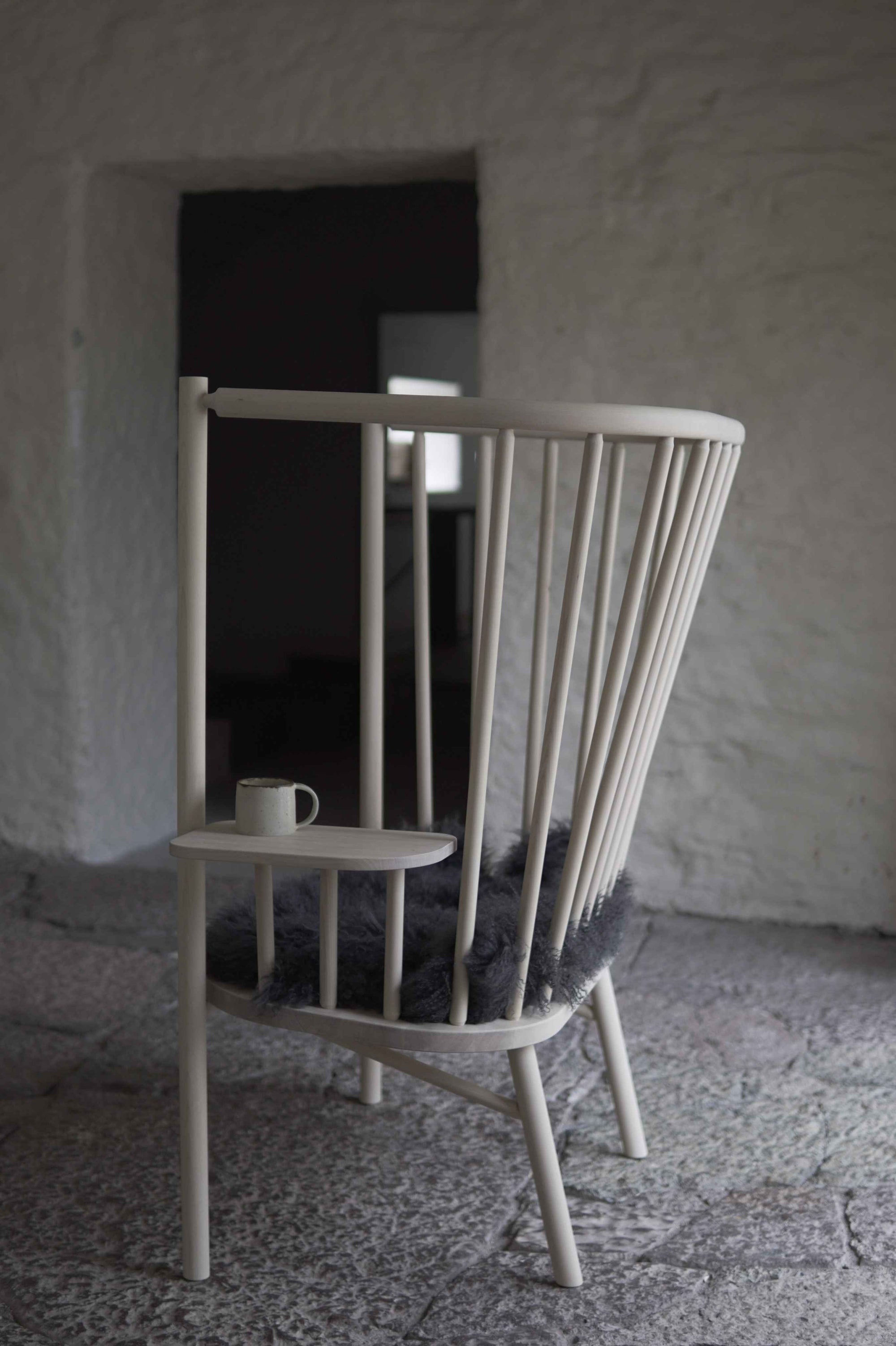 Wooden chair with a small table and cup against a textured wall.
