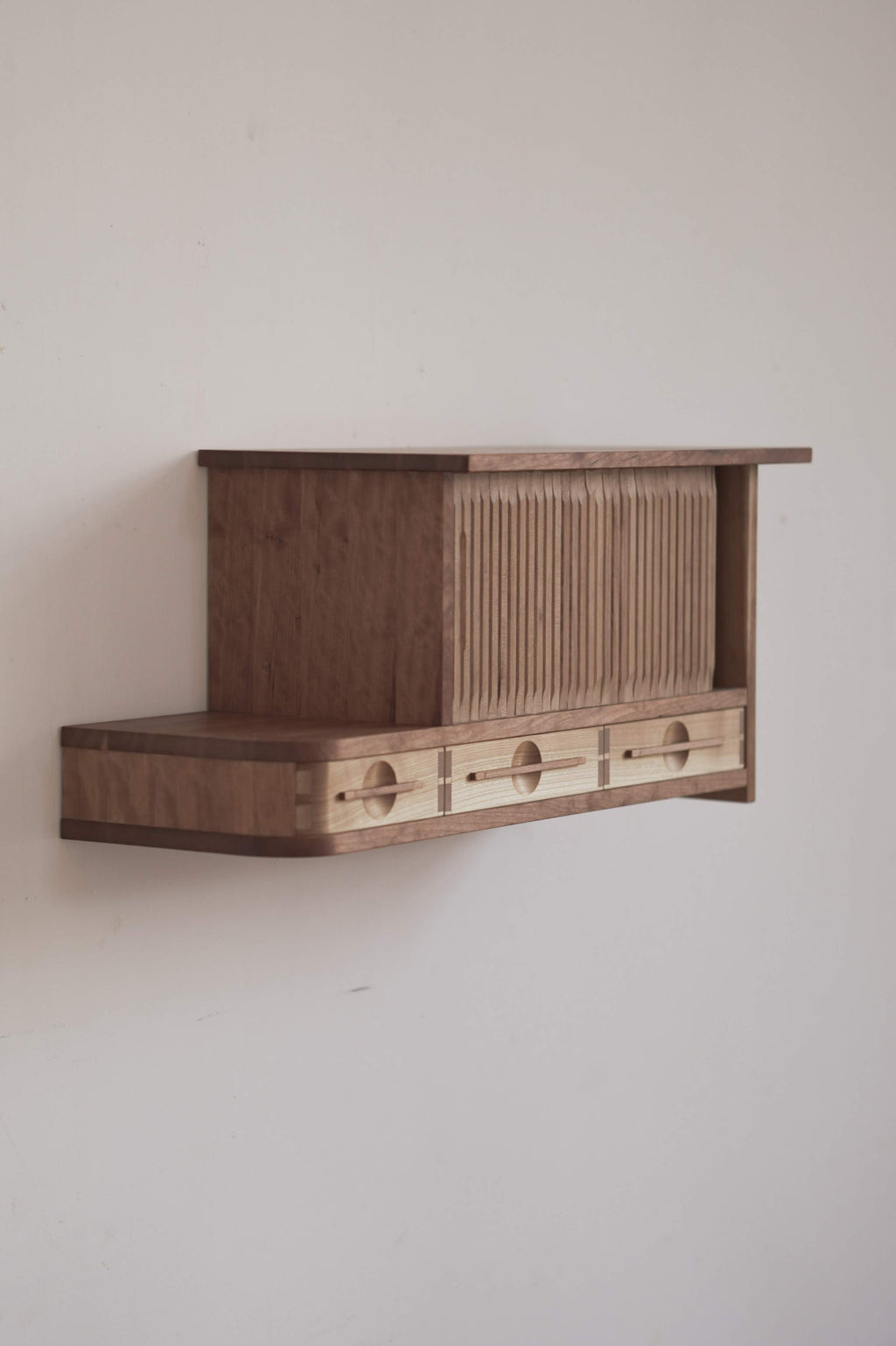 Wooden cabinet with tambour doors on a plain wall