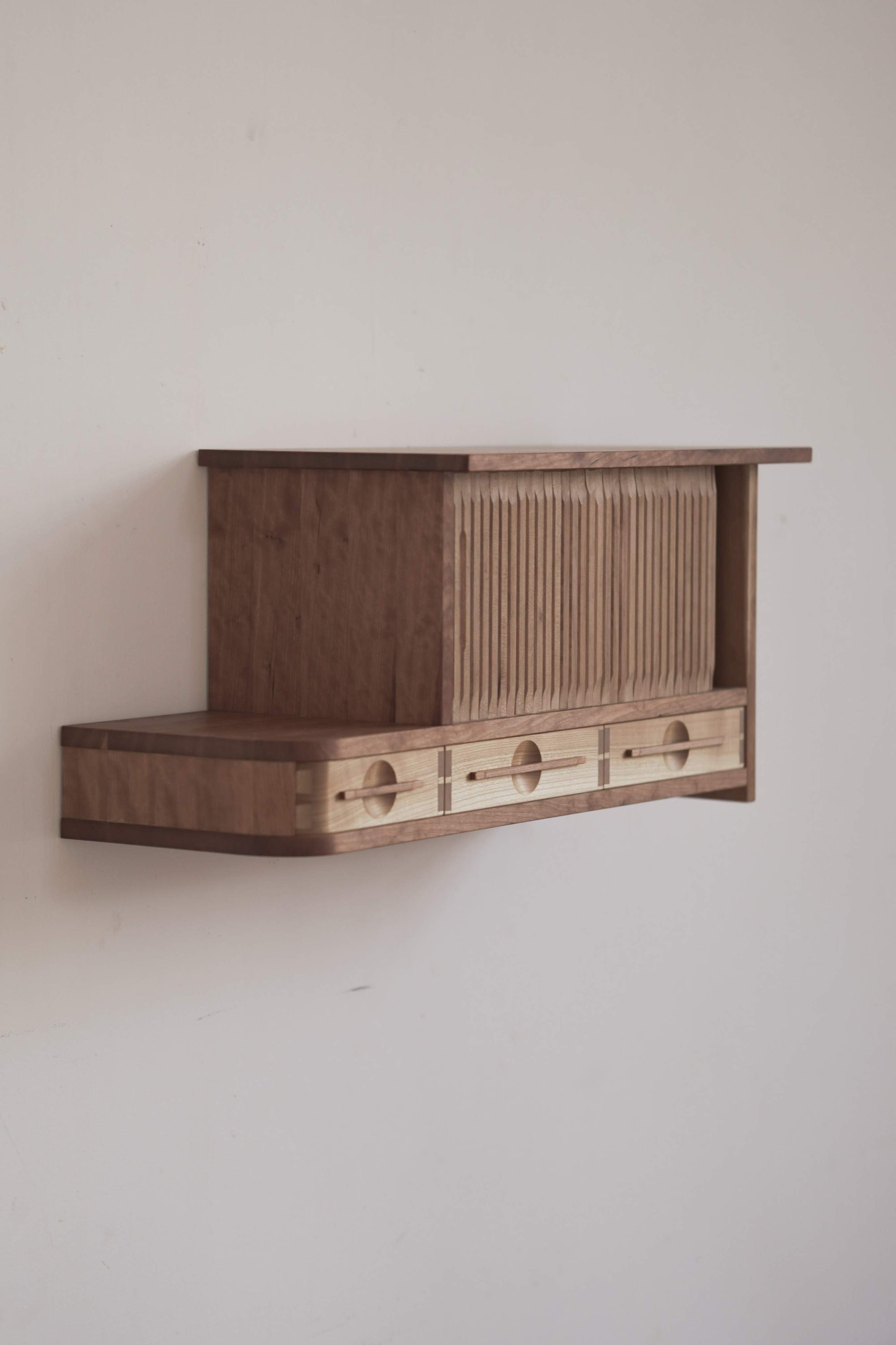 Wooden cabinet with tambour doors on a plain wall