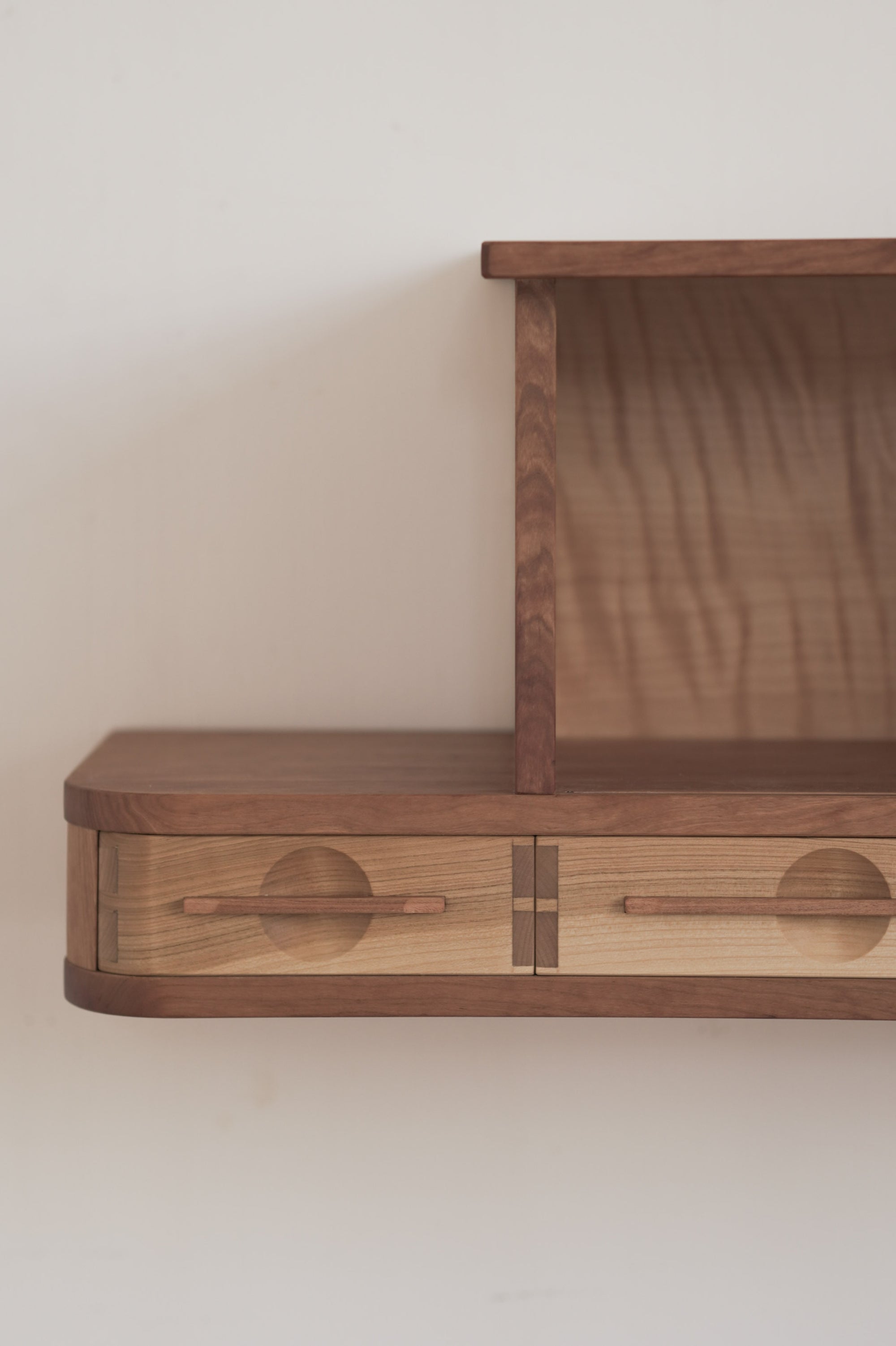Closeup of a wooden cabinet with tambour doors on a plain wall