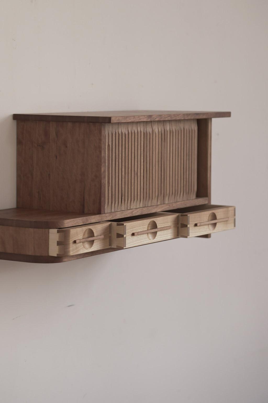 Wooden cabinet with tambour doors on a plain wall