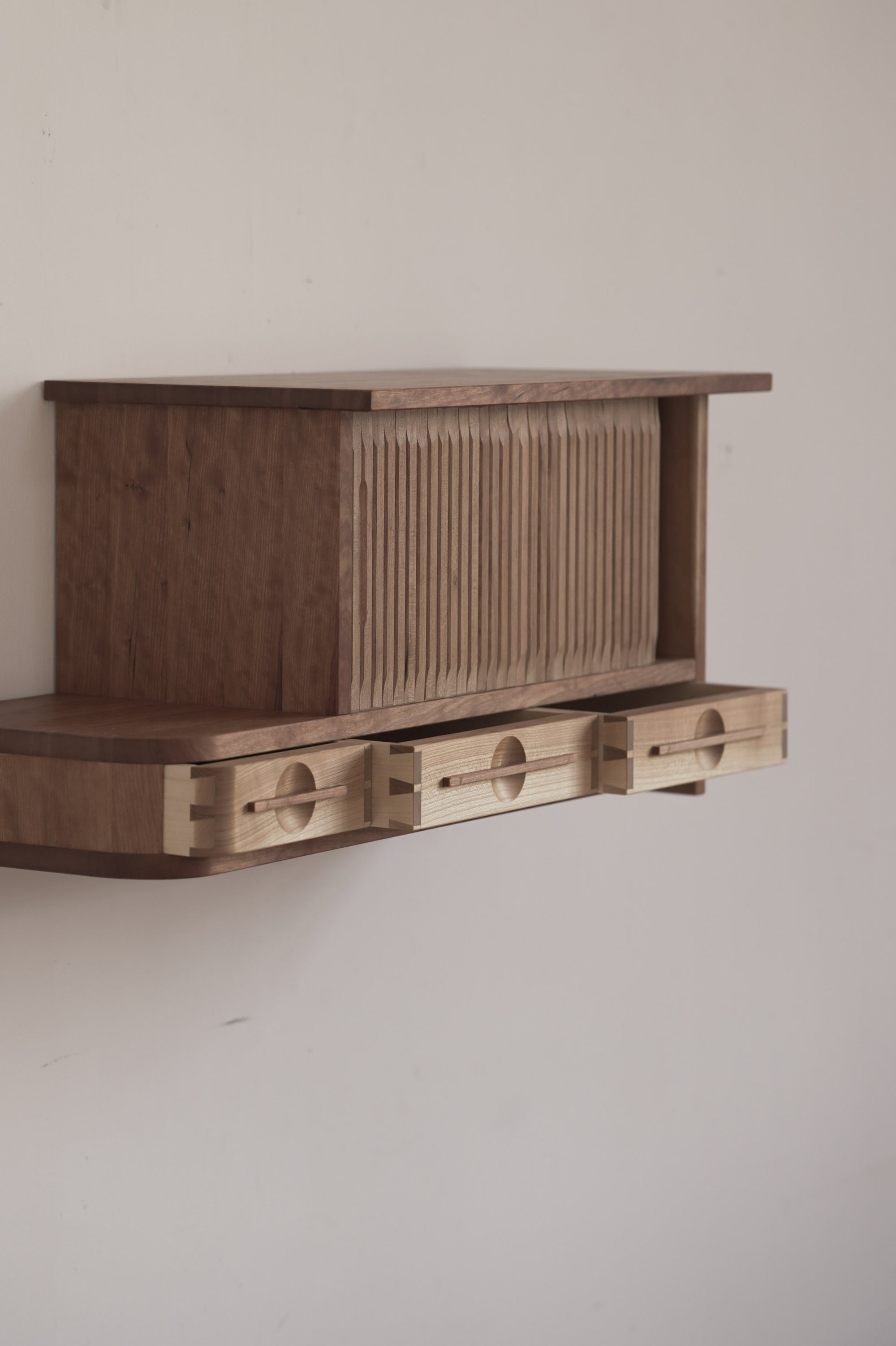 Wooden cabinet with tambour doors on a plain wall